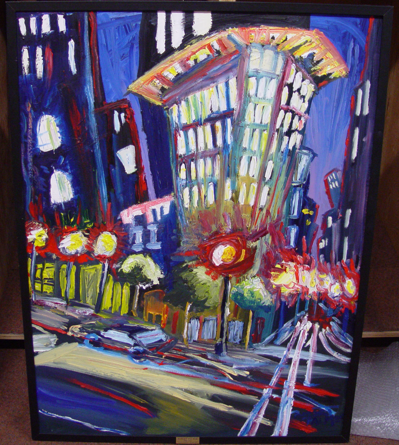 "The City" by Robert Palmer. Oil painting depicts stylized city scape of a building on the corner of the street. The scene is at night. Bright street lights and windows. 